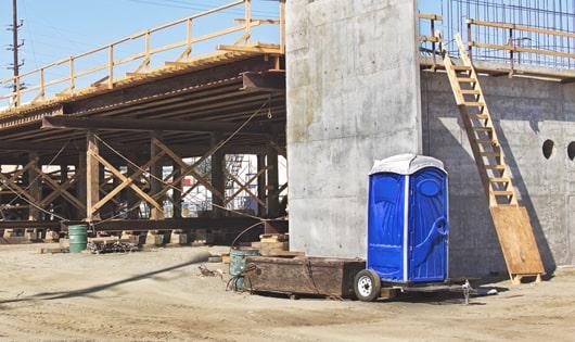 blue portable restrooms arranged in a neat line on a construction site